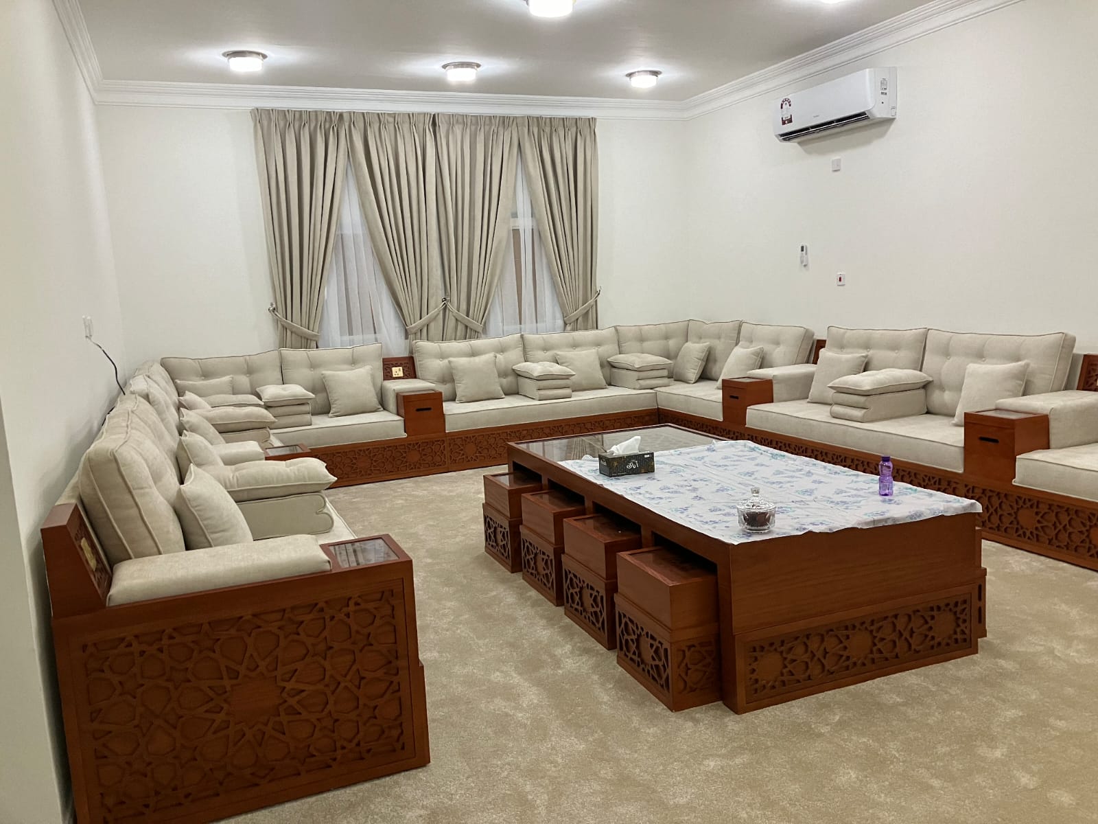 Custom-made majlis seating running along three walls of a Qatari living room with a matching low table